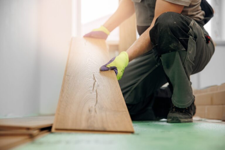 Engineered Wood Floor Installation – craftsman eases a wide engineered oak plank into a click-lock joint over green acoustic underlay