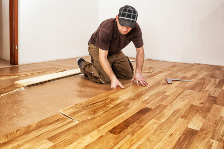 Close-up of a craftsman precisely marking an oak plank during Junckers Floor Fitting to achieve a seamless Scandinavian look.