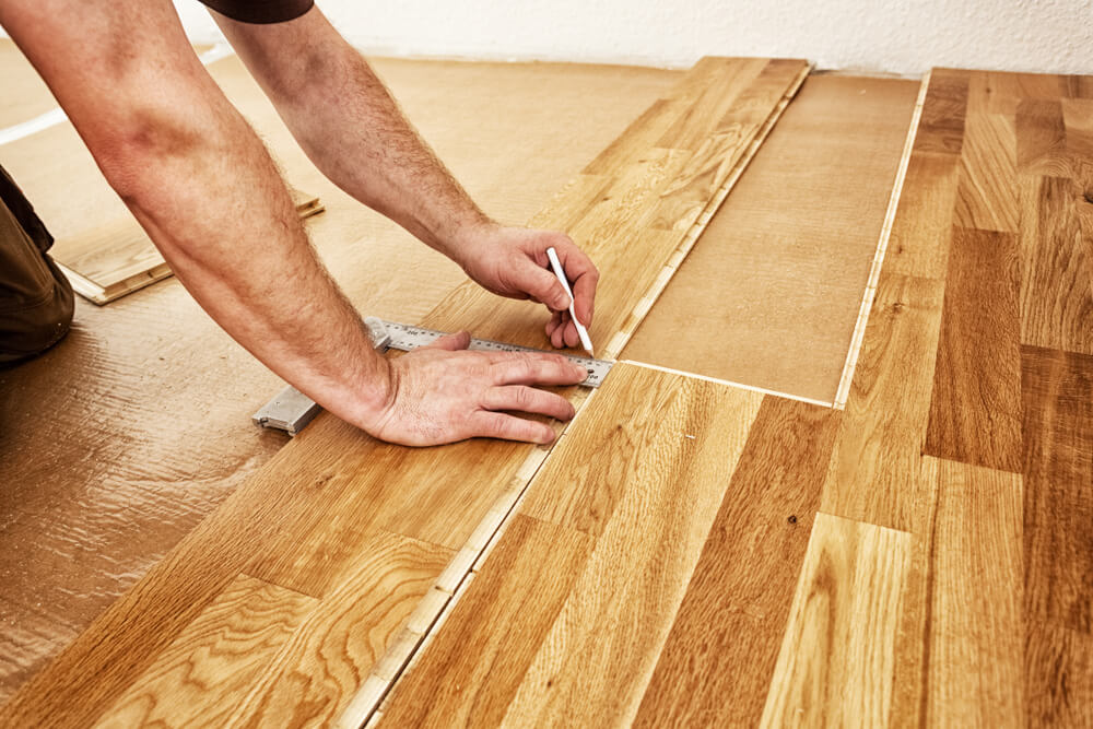 A Mr Sander professional measuring wooden planks for Engineered Floor Installation in London