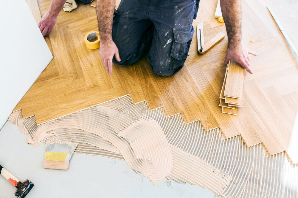 Floor fitter carefully installing a herringbone parquet pattern during a South London floor fitting project.