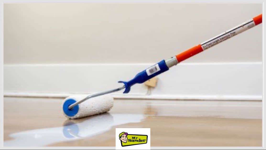 A close-up of a roller brush applying a smooth layer of finish on a polished wooden floor, showcasing professional-grade flooring restoration.