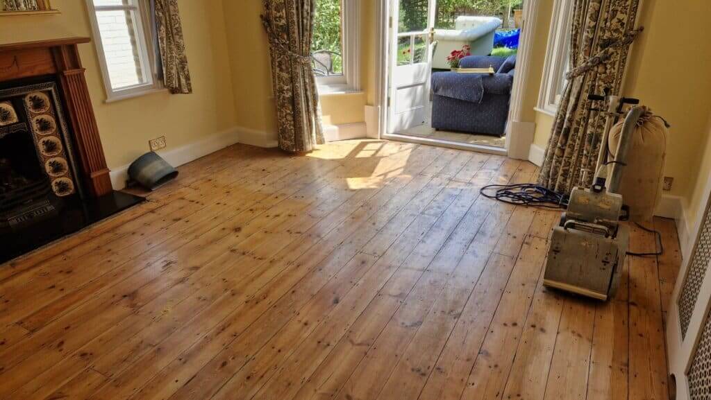 Mr Sander® professional machine is sanding a pine floor in a living room using a Bona Belt sander (AMO110000.3). The machine features a 2.2 kW motor, 230 V voltage, 50 Hz frequency, and a sanding belt size of 200 x 750 mm or 250 x 750 mm. The total weight is 74 kg.