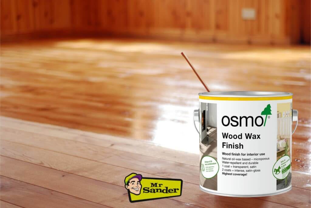 A can of Osmo Wood Wax Finish placed on a beautifully refinished wooden floor. The background shows the shiny, polished surface of the floor, highlighting the effectiveness of the wood wax finish. The Mr Sander® logo is displayed at the bottom of the image.