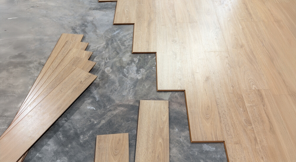Laminate floor planks arranged on a concrete subfloor, prepared for installation by Mr Sander in London
