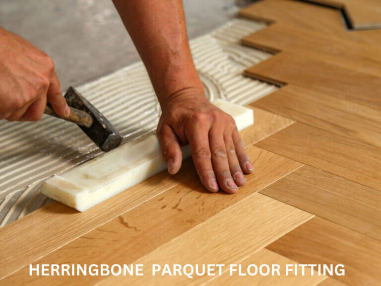 Close-up of a floor fitter precisely aligning herringbone wood parquet boards using adhesive during a West London Floor Fitting project.