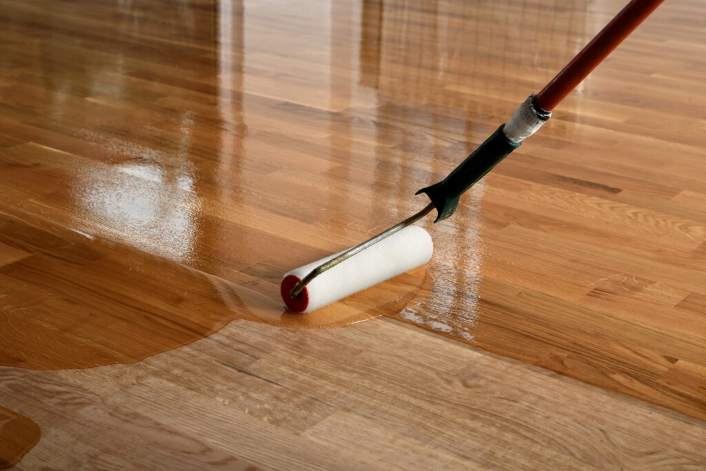 The process of lacquering wood floors involves a skilled worker using a roller to evenly apply the coating, resulting in a beautifully finished surface.