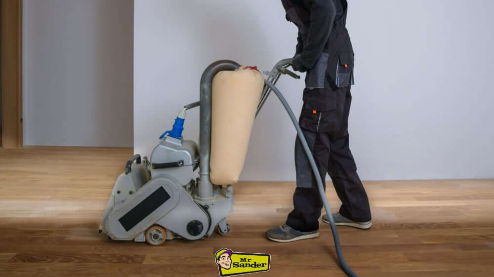 A worker using a floor sander on a hardwood floor.