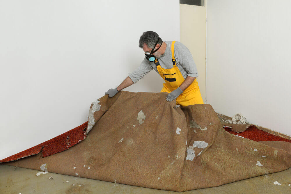 A professional removing old carpet in preparation for a South London floor fitting.