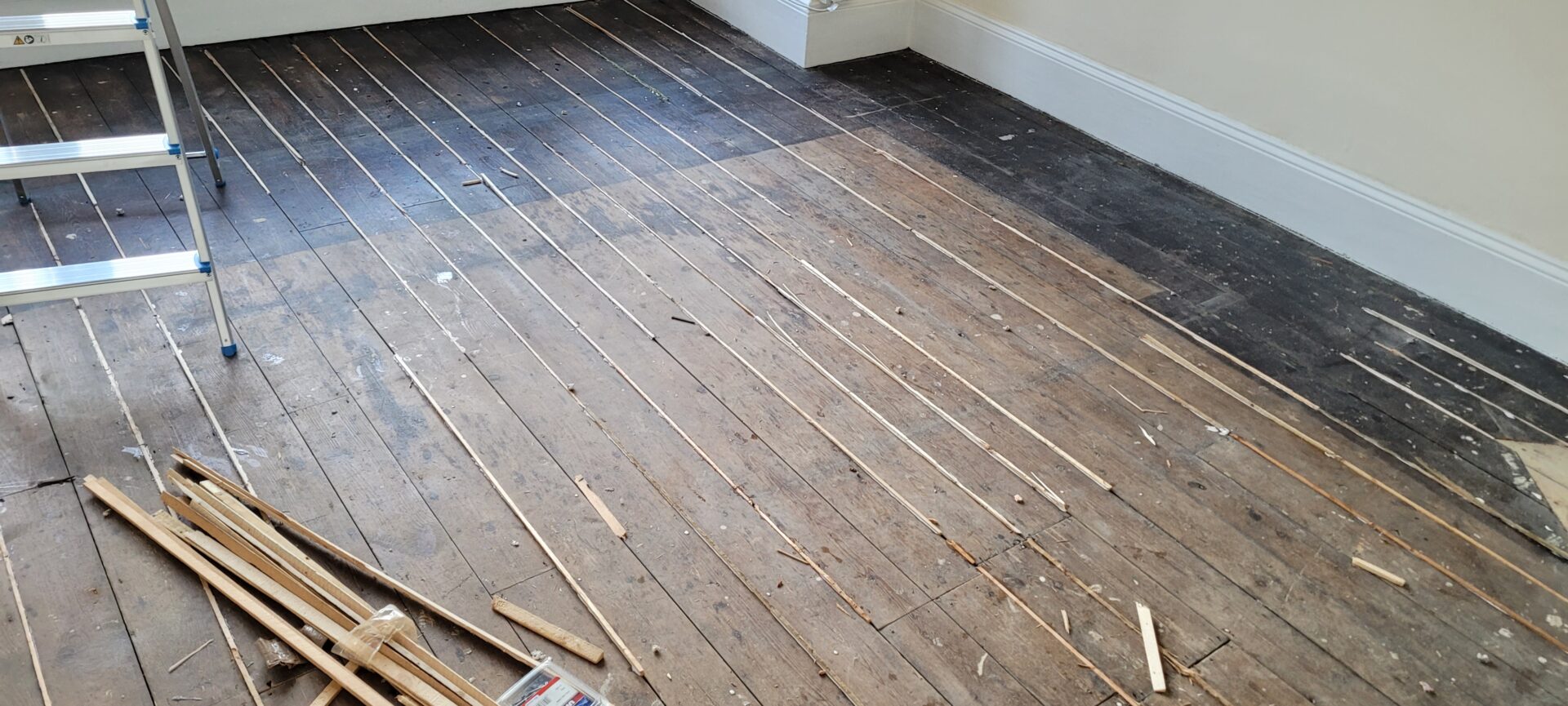 Repairing Gaps Between Floorboards with pine slivers in a British period room before sanding