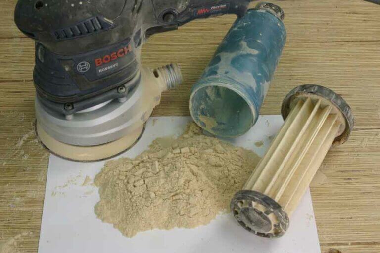 Orbital sander connected to a dust extraction system showing clean, efficient sanding with minimal airborne dust.