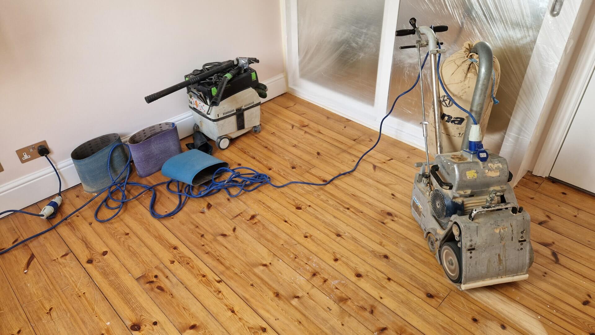 A floor sanding setup by Mr Sander, including a belt sander, dust extractor, and sanding belts, highlighting that Sanding Wooden Floors is Very Easy.