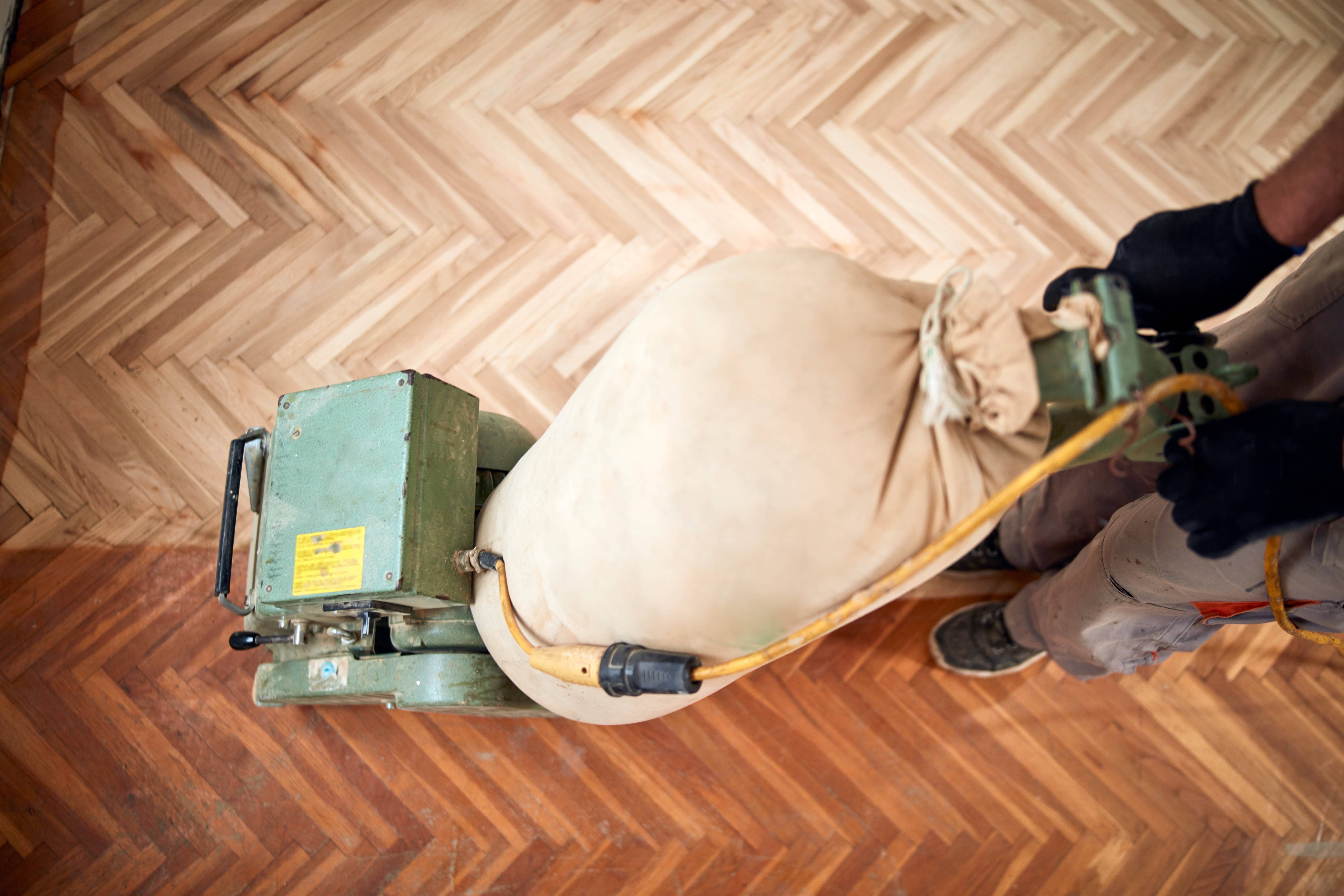 In Streatham, SW16, Professional Mr Sander® sanding a herringbone floor using the powerful and compact Bona Belt Lite belt sander. With a 2.2 kW motor, 230V voltage, and 50Hz frequency, this efficient sander measures 200x750 mm in size. The sander is connected to a dust extraction system equipped with a HEPA filter, ensuring a clean and efficient result. 