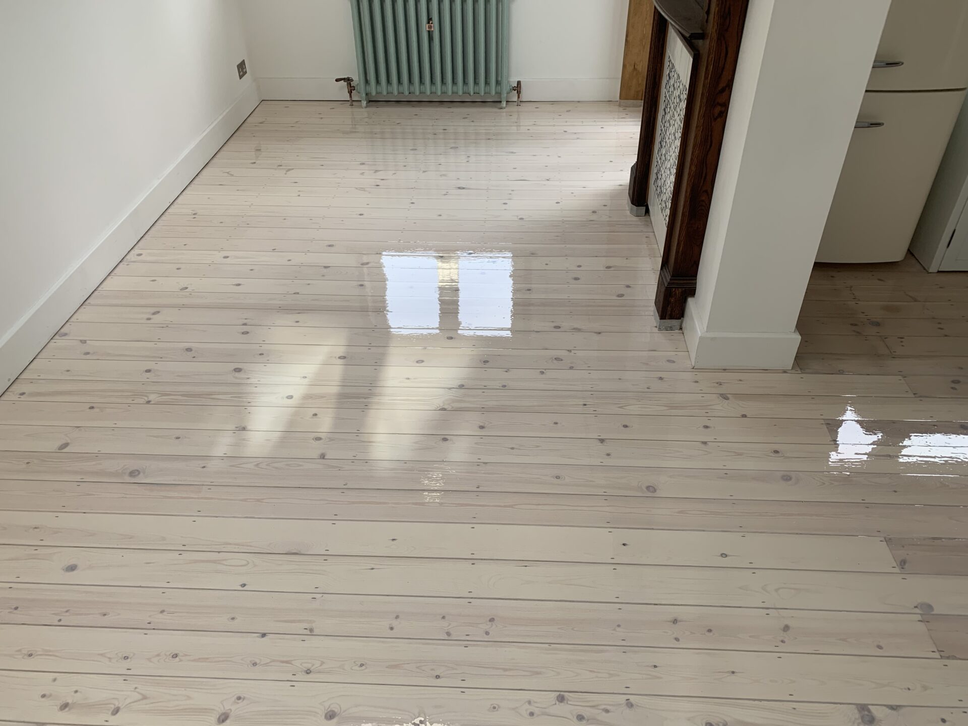 A pale, newly refinished pine floor coated with Bona White Primer, reflecting natural light from the window.