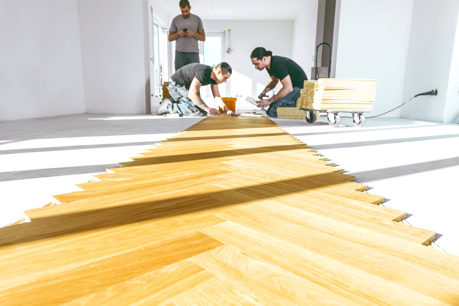 Flooring team laying an oak herringbone pattern during a Parquet Floor Fitting in a bright, modern room