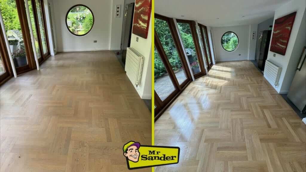 A before and after comparison of a modern room with large floor-to-ceiling windows and herringbone wood flooring. The left image shows the floor in a dull and faded condition, while the right image displays the same floor after being sanded and refinished, appearing brighter and more polished. The room features a round window at the end and a red painting on the wall.