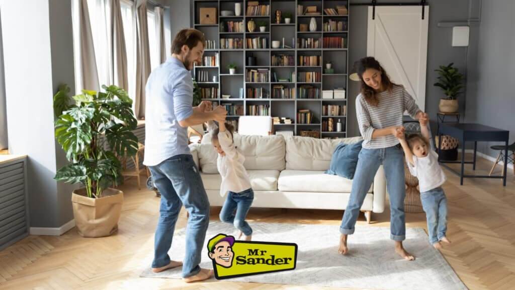 A joyful family playing in a bright, modern living room with beautifully sanded and finished wooden floors, restored by Mr Sander® in Southgate.