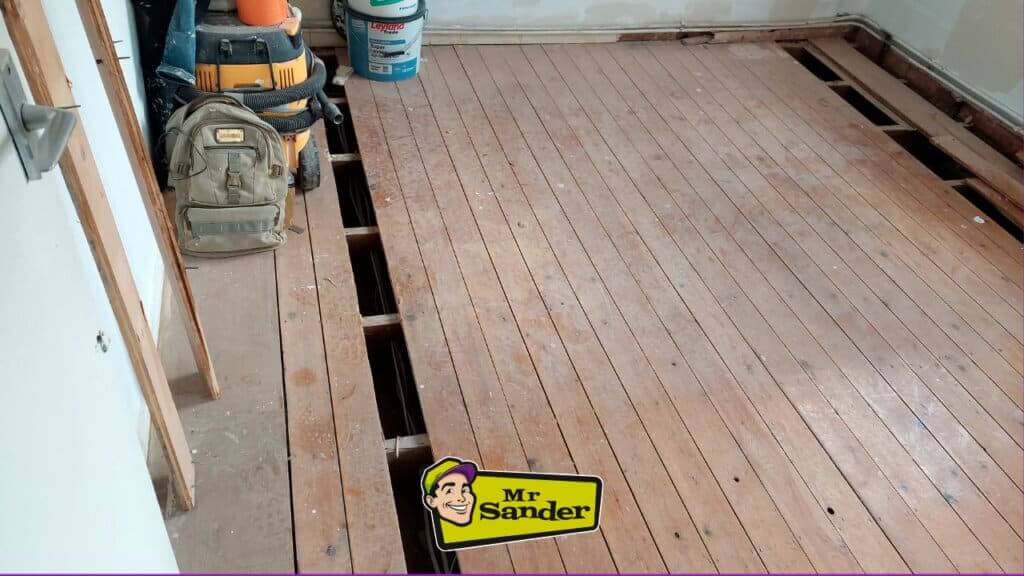  A close-up of a damaged hardwood floor with a watermark of Mr. Sander's logo.
