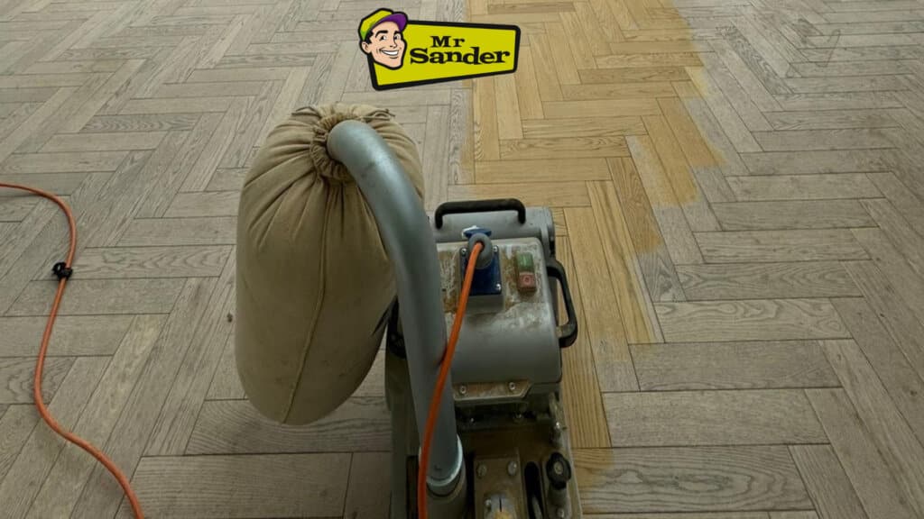 Man from Mr Sander® sanding parquet floor in a living room in Stanmore, UK, using Bona Belt sander (AMO110000.3), 2.2 kW motor power, 230 V, 50 Hz, 250x750 mm size, 200 & 250 mm drum width, sanding belt size 200x750 mm or 250x750 mm, total weight 74 kg, for precise and efficient sanding.