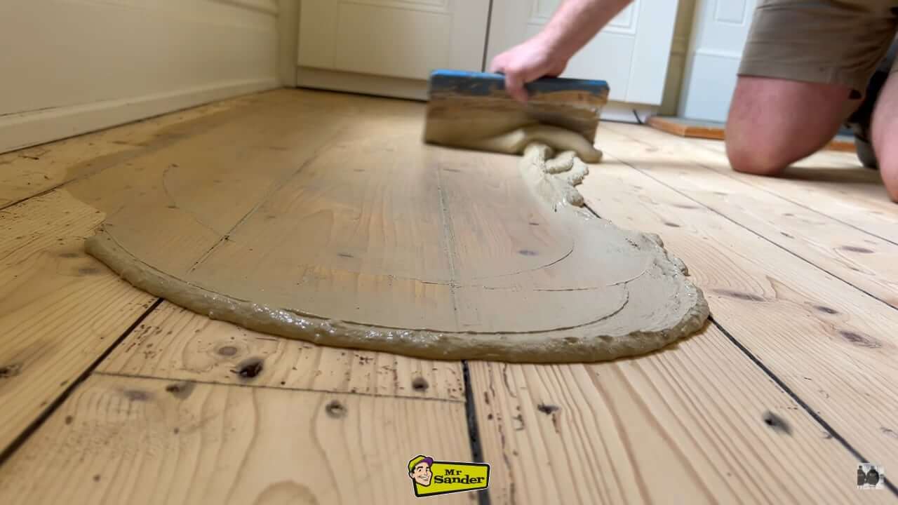 Floor sanding and filling in progress at Stanwell Moor, showing a skilled professional applying filler to restore pine floorboards for a seamless finish.