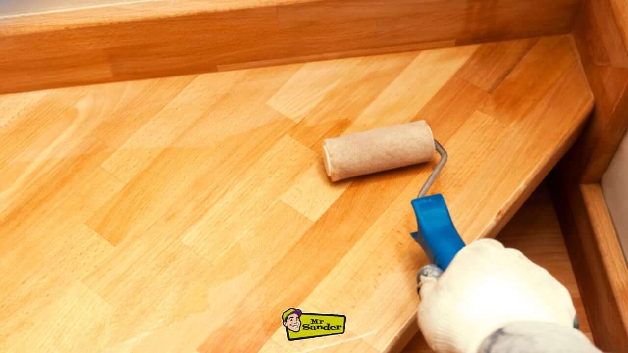 A close-up of a professional applying a smooth finish to a freshly sanded wooden stair surface using a roller at Strawberry Hill.