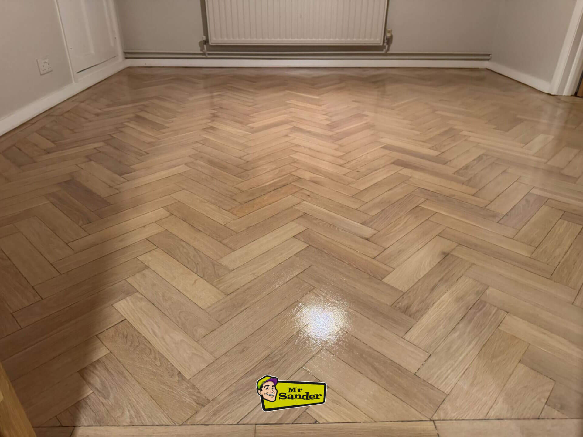 A newly installed herringbone parquet floor with a glossy finish, demonstrating professional West London Floor Fitting craftsmanship.