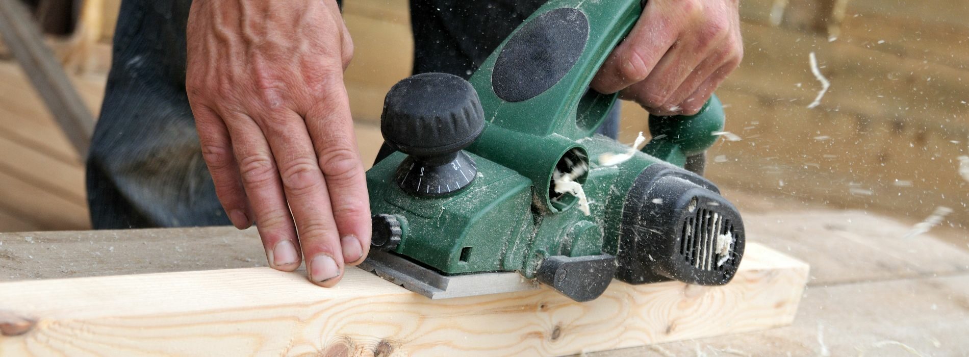 A person using a power tool on a piece of wood.