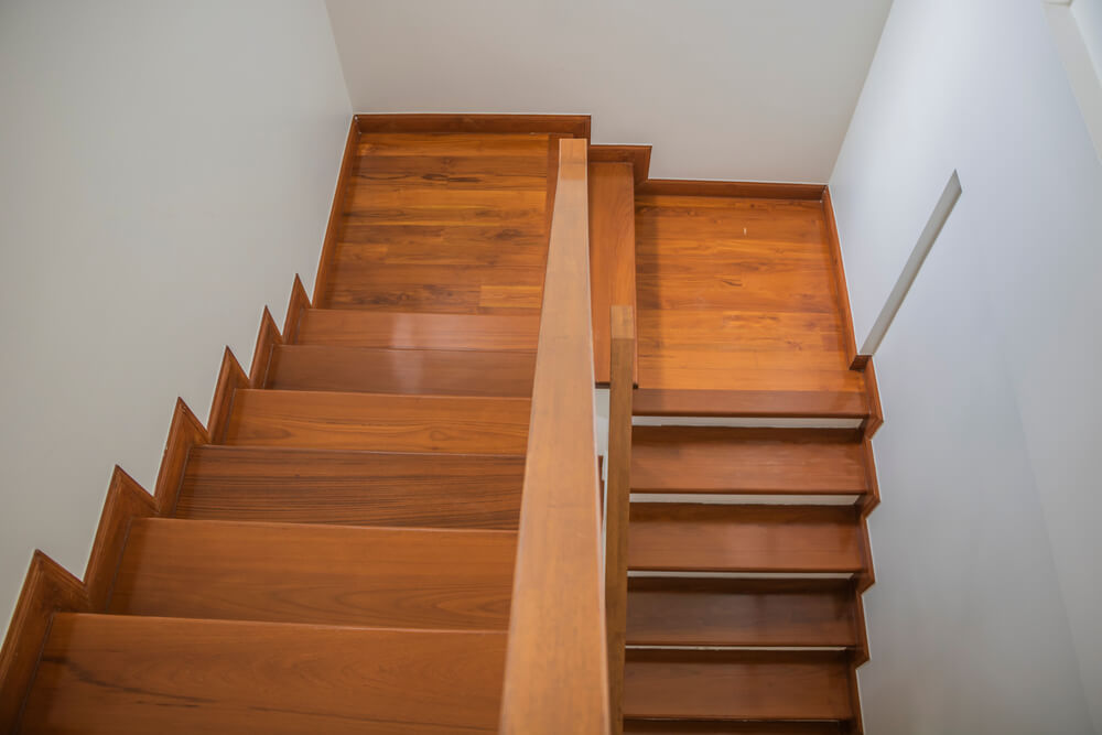 An overhead view of a modern teak staircase, newly refinished after a comprehensive wooden stairs sanding, repair, and restoration project by Mr Sander in London.