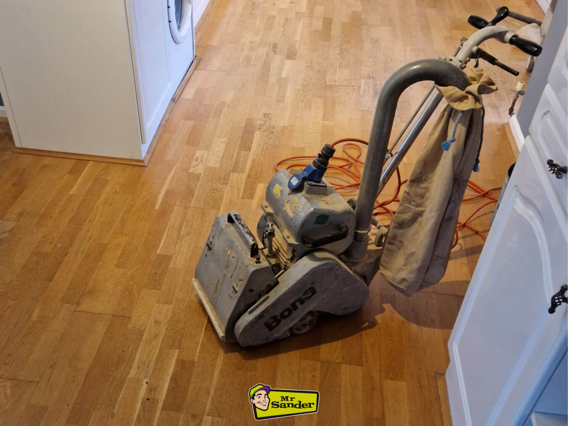 A professional floor sanding machine poised on a partially sanded wooden floor, illustrating The Art of Floor Sanding in progress.