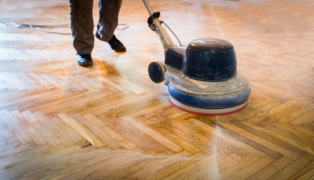 A floor buffer machine polishing a wooden parquet floor.