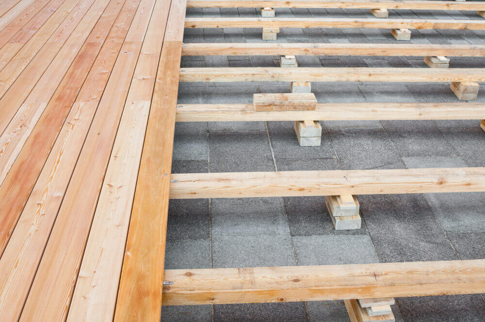 An elevated wooden deck structure with visible joists, supporting newly laid boards, creating a stable base for a floor installation.