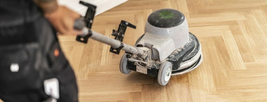 Mr Sander® professional using a Lagler SINGLE sander in a living room in Tottenham, UK. This powerful machine is designed for precision, intermediate sanding, and complex underfloor preparation. Features include a 230V single-phase AC motor, 406 mm sanding disc, 180 rpm speed, and weighs 45 kg.