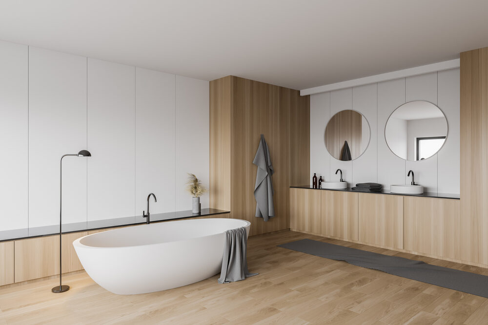 A spacious modern bathroom with a wooden floor, freestanding bathtub, and sleek wood panel accents, illustrating the premium results of ‘Floor Sanding for Bathrooms.