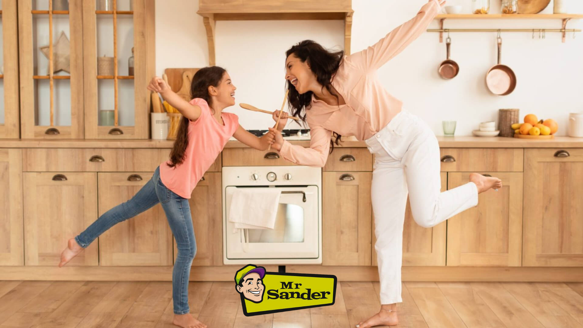 A joyful mother and daughter dancing in their kitchen, enjoying the beautifully restored wooden floor by Mr Sander® in Tufnell Park.