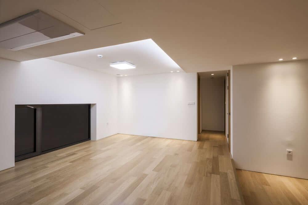 Spacious modern living room in Gants Hill, UK, with newly sanded and refinished oak hardwood floors, completed by Mr Sander®. The smooth, polished surface enhances the room's minimalist aesthetic, highlighting the quality of the wood and the craftsmanship of the floor treatment.