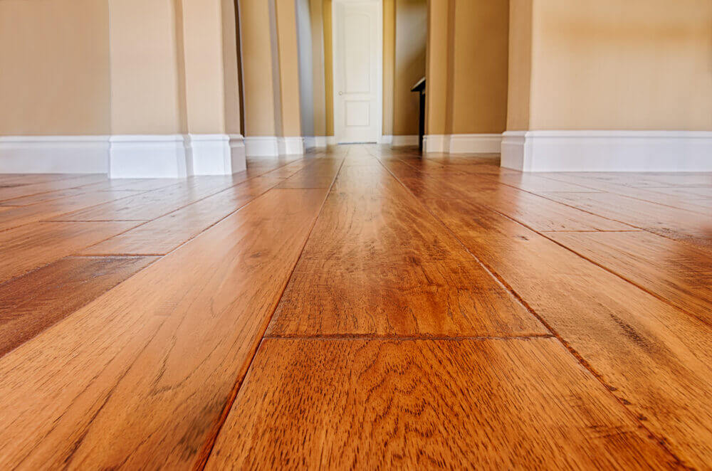 Low-angle view of freshly installed wood planks, capturing the smooth and polished result of expert Hardwood Floor Fitting.