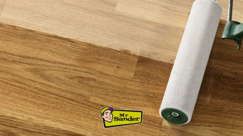 A roller applying finish to a newly sanded wooden floor, featuring the logo of Mr. Sander®.