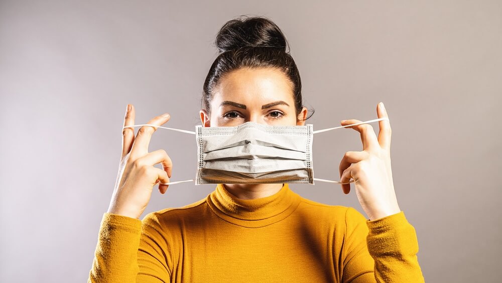 A woman adjusting a protective face mask to help prevent inhalation of sawdust or floor sanding dust.