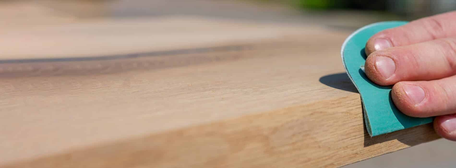 A close up of a person's hand holding a piece of wood.