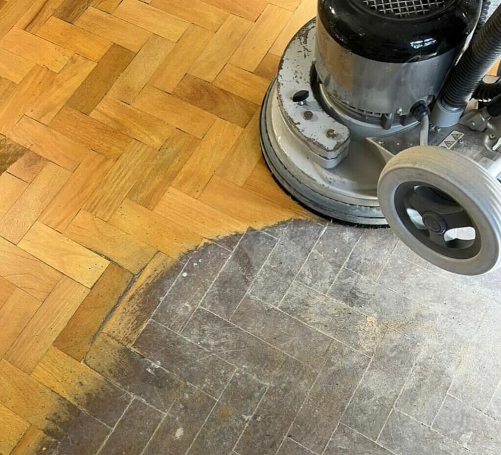 A professional from Mr Sander® sands a living room floor in Richmond, UK, using a Bona FlexiSand 1.9 (AMO310002) buffer. The machine has dimensions of Ø 407 mm, a motor power of 1.9 kW, voltage of 230 V, and frequency of 50 Hz. It features a 16 A overload switch and thermal protection, with an abrasive disc speed of 147 rpm. The total weight is 50 kg.