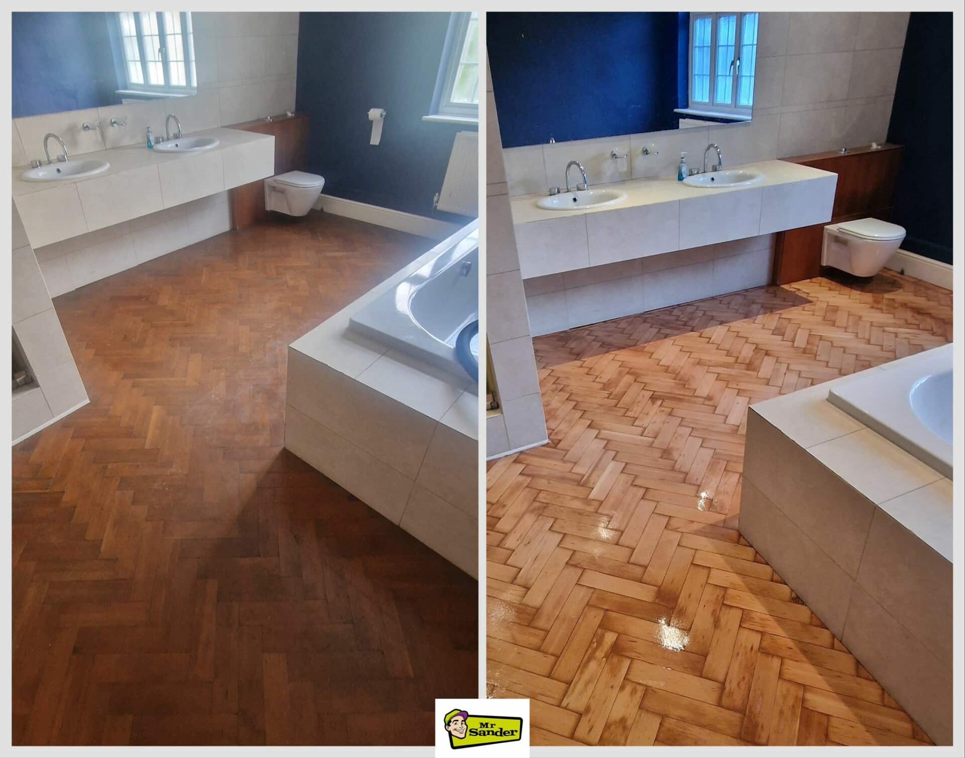 A two-part image showing the before and after stages of a bathroom floor sanding and refinishing project by Mr Sander®. The left part shows the bathroom with a dark, worn herringbone wooden floor. The right part shows the same bathroom with the floor beautifully sanded and refinished to a light, glossy finish. The room features a double sink, a toilet, and a bathtub, with white tiles and dark blue walls.