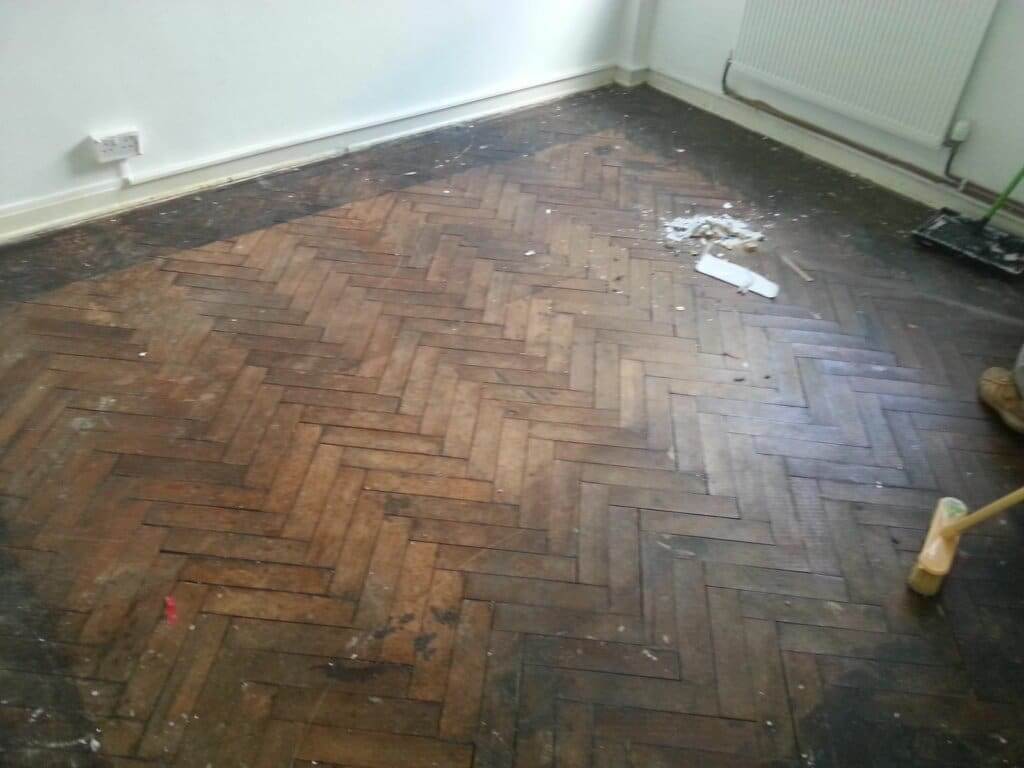 A worn and damaged parquet floor in need of restoration, with visible scratches, dirt, and discoloration. The image shows the initial state of the flooring before the professional parquet flooring restoration process by Mr Sander®. This highlights the significant transformation that can be achieved through expert restoration services.