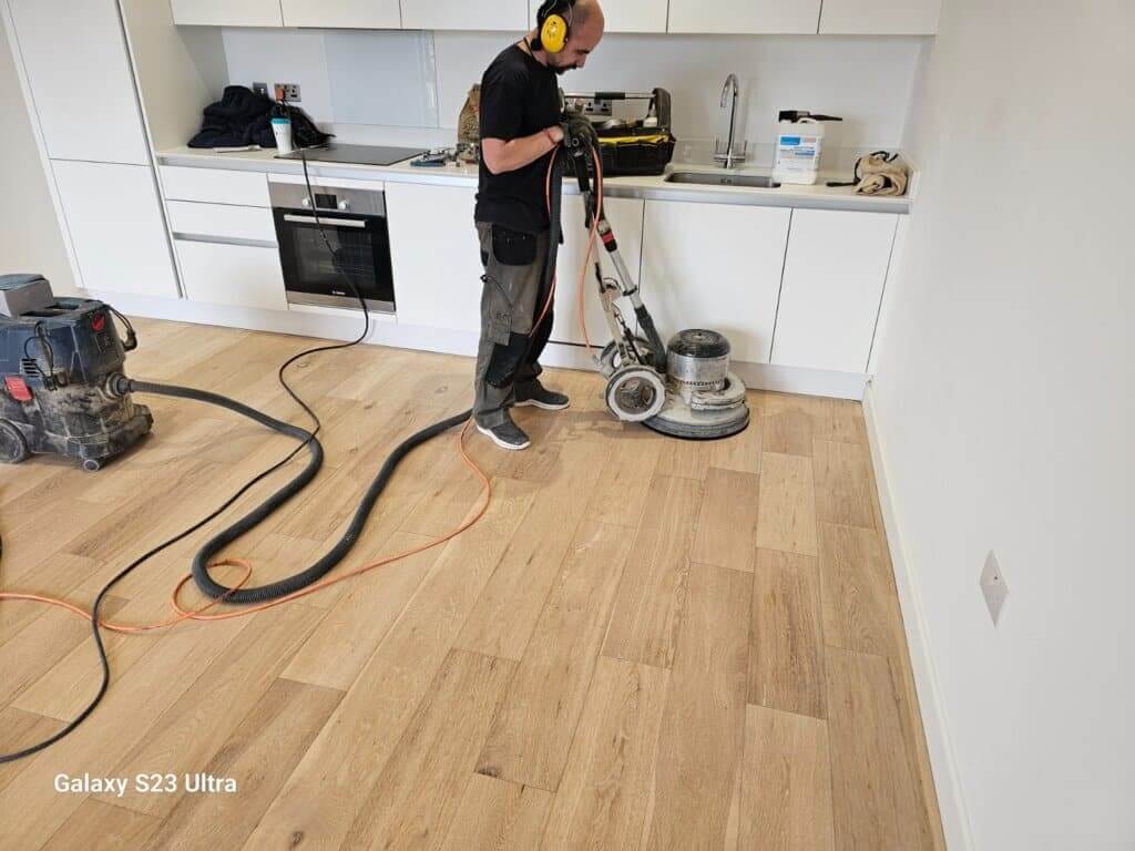 Professional oak floor sanding in, UK living room by a Mr Sander® technician using Bona DCS 70 dust containment system (AMO530005), featuring 230V, 50/60Hz, 1400W motor power, 70L dust holding capacity, and HEPA class H 13 fine filter. Additionally, employing Bona FlexiSand 1.9 (AMO310002) with Ø407mm dimensions, 1.9kW power, and 230V, 50Hz frequency.