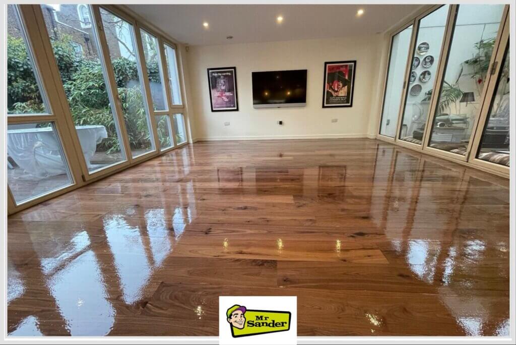 A newly refinished hardwood floor with a glossy finish, reflecting light from large windows.