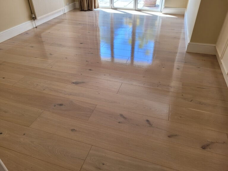 A newly whitewashed oak floor with a glossy reflection, illustrating how Junckers White Prelak accentuates the natural wood grain.