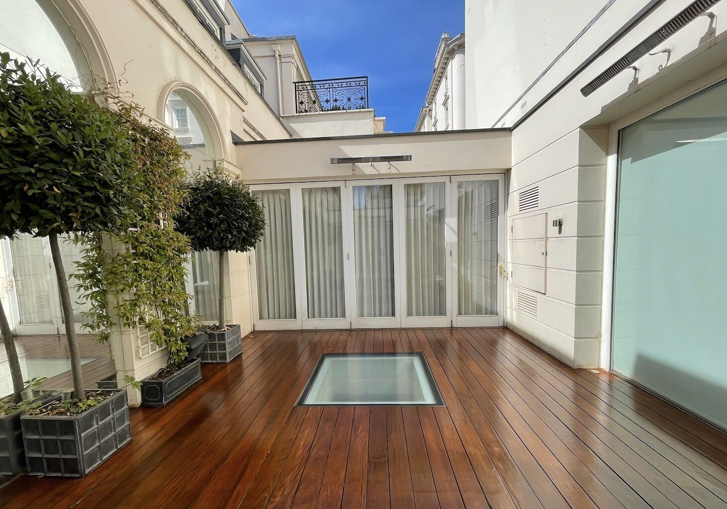 Anger at Aging Decks: freshly restored hardwood timber decking on a modern terrace, showing a rich oiled sheen and a flush rooflight in the centre.