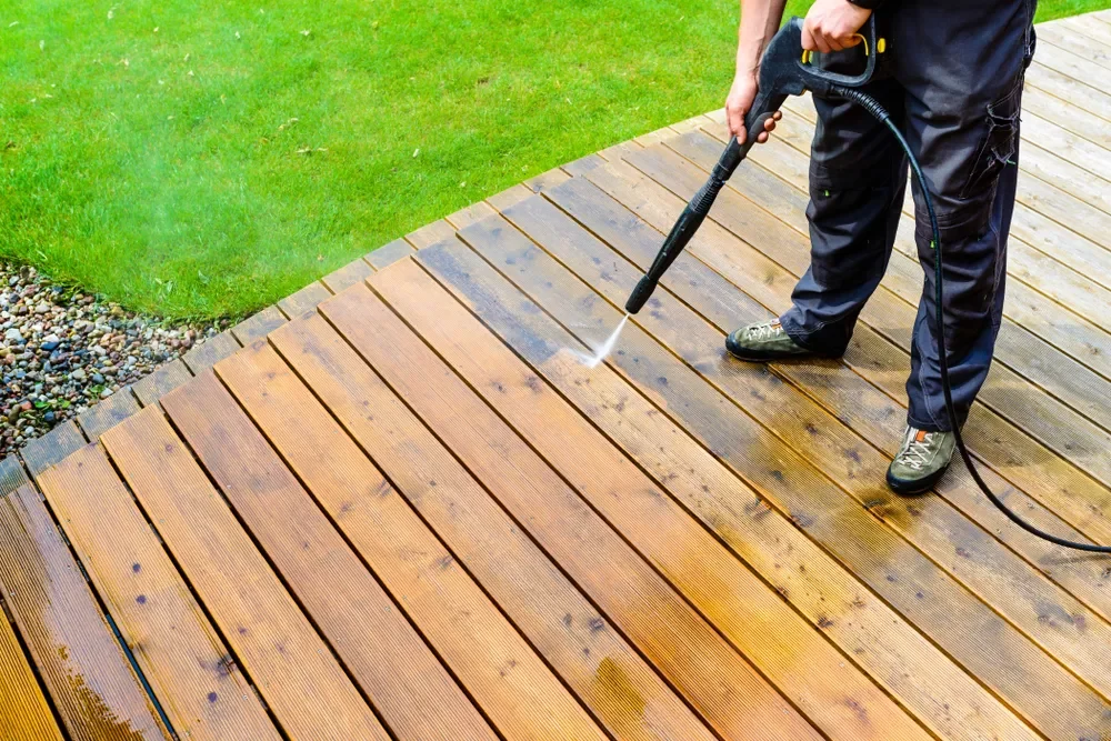 Anger at Aging Decks: pressure washing grooved softwood timber decking to remove dirt, algae, and stains before sanding and refinishing.