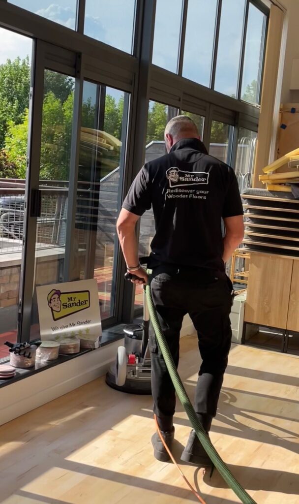 Mr. Sander® technician performing dustless floor sanding on a wooden floor using a Festool Rotex 150 orbital sander, seamlessly connected to a Bona dust extraction system. This ensures a clean, efficient, and professional sanding process with minimal dust for superior results.