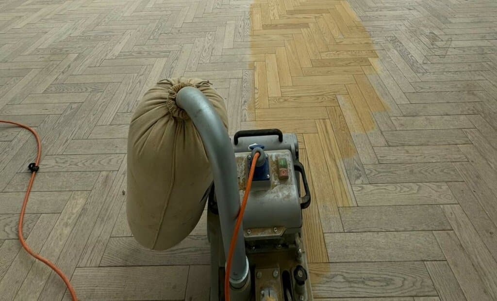 Man from Mr Sander® sanding parquet floor in a living room in Chinatown, UK, using Bona Belt sander (AMO110000.3), 2.2 kW motor power, 230 V, 50 Hz, 250x750 mm size, 200 & 250 mm drum width, sanding belt size 200x750 mm or 250x750 mm, total weight 74 kg, for precise and efficient sanding.