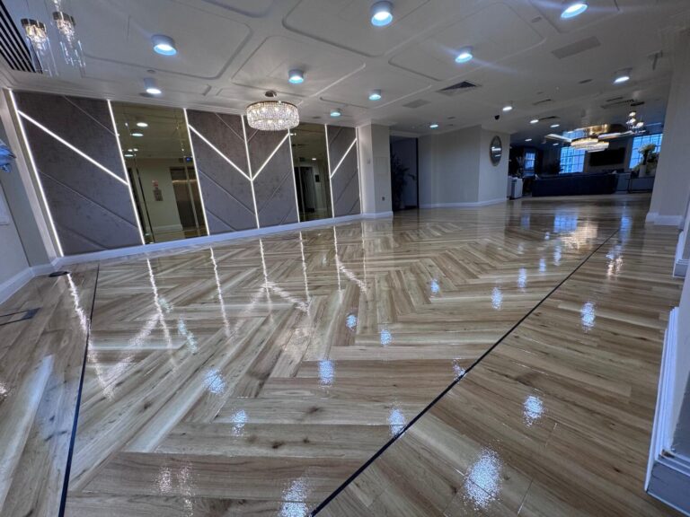 Luxurious ballroom with engineered European oak chevron parquet, freshly finished to a high-gloss sheen; crisp black feature border emphasises alignment during Chevron Install.