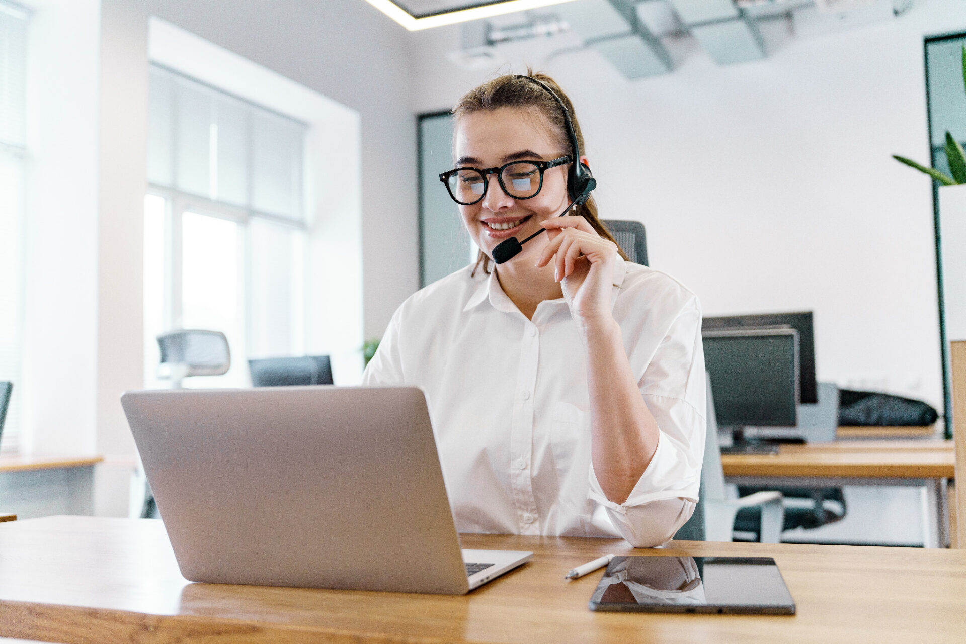 Customer service advisor on a headset helping a client with Chevron Parquet Installation for an oak engineered hardwood floor in a bright modern office.